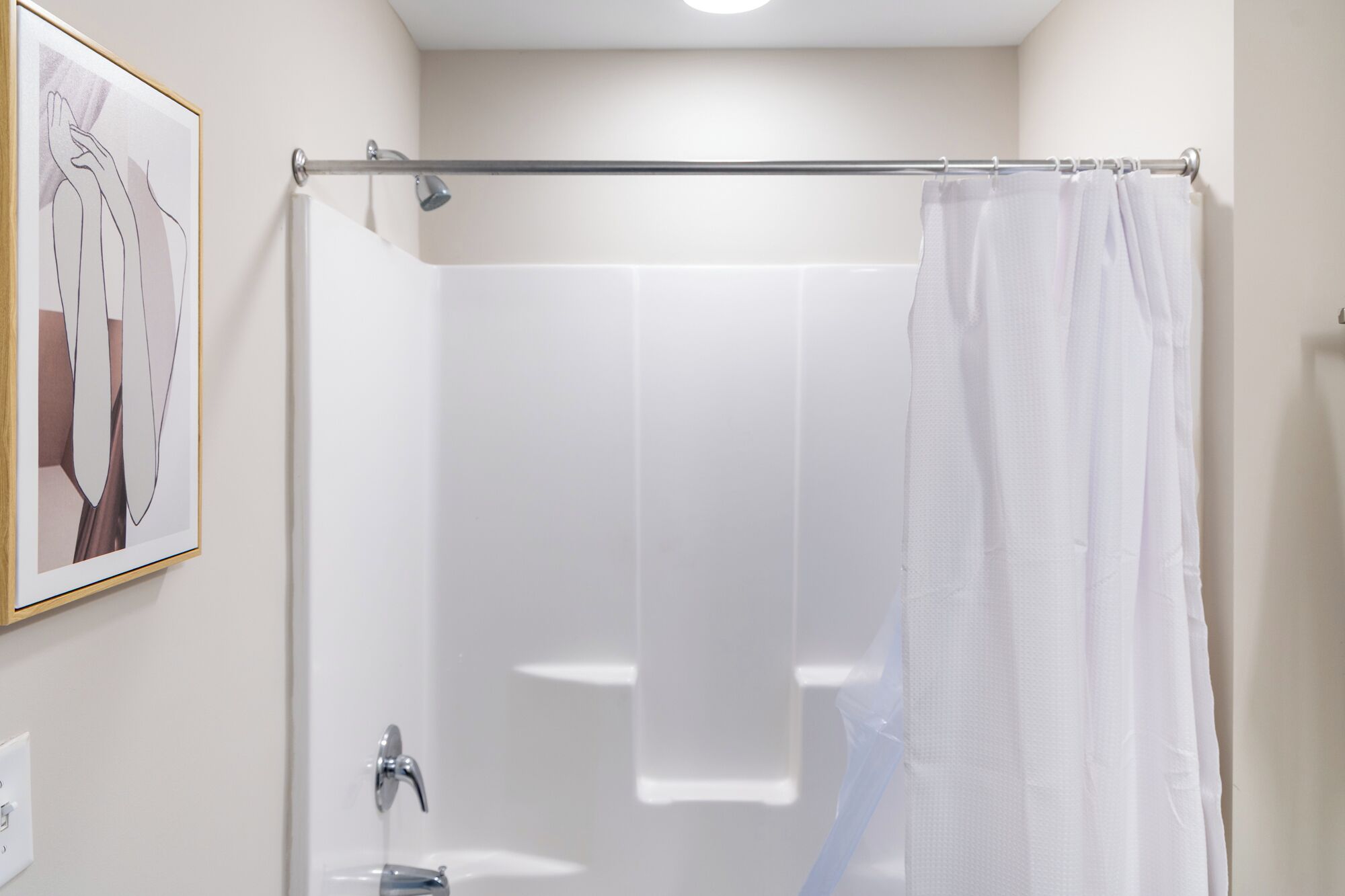 Een badkamer met een douche, een handdoekhouder en een fotokader aan de muur.