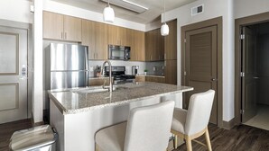 Eine moderne Küche mit Granit Arbeitsplatten, Edelstahlgeräten und Holzschränken.