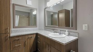 A bathroom with a granite countertop, a white sink, and wooden cabinets.