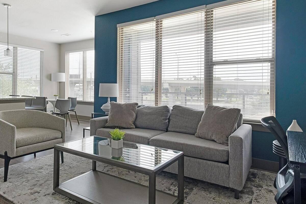 A modern living room with a sofa, coffee table, and a kitchen area in the background.