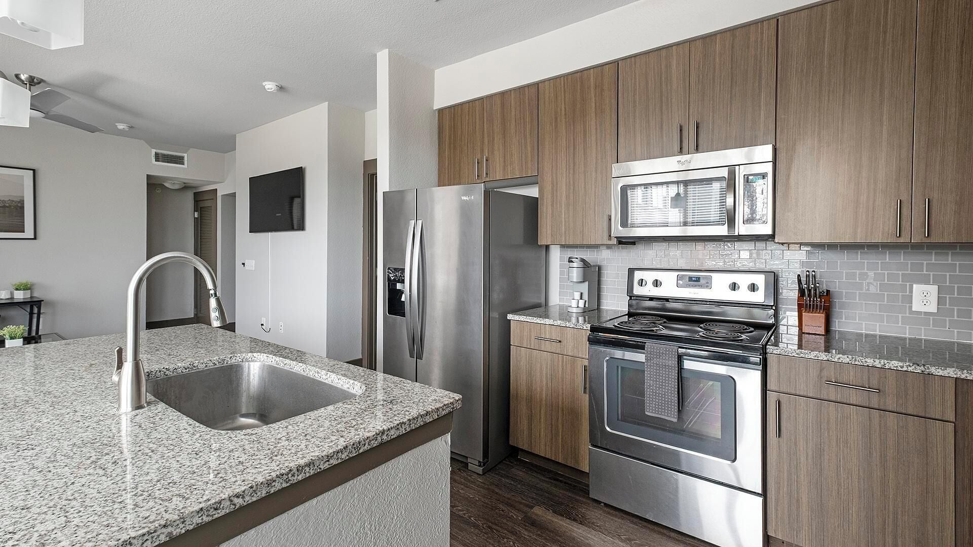 A modern kitchen with granite countertops, stainless steel appliances, and wooden cabinets.