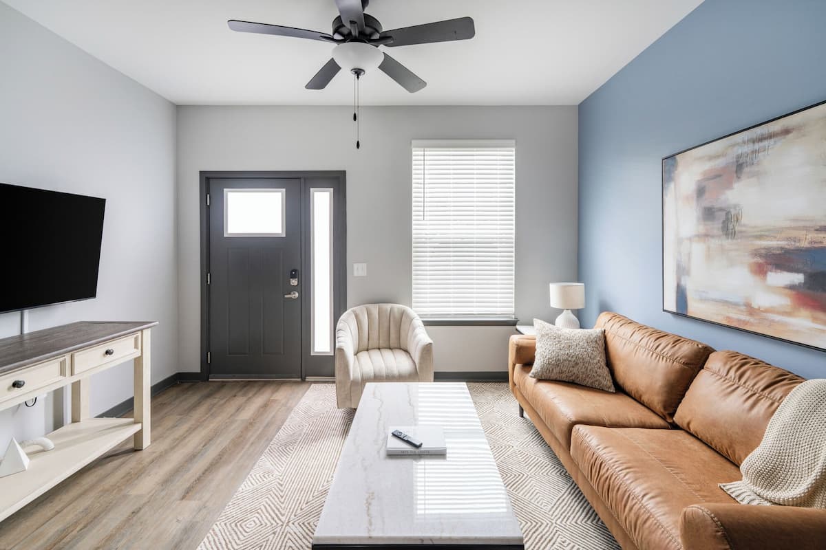 A modern living room with a television, sofa, coffee table, and a ceiling fan.