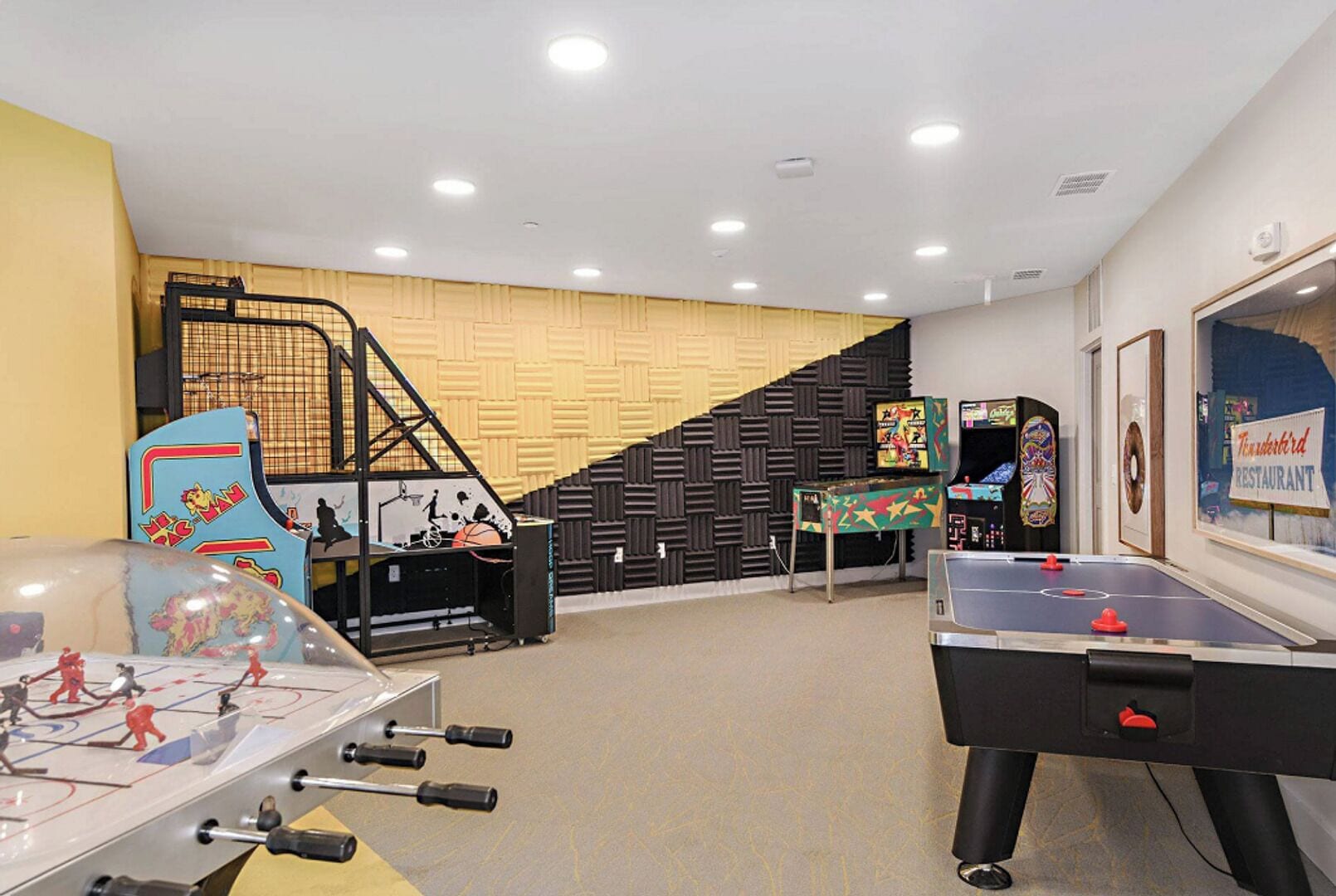 A recreational room with a foosball table, a ping pong table, and arcade games.