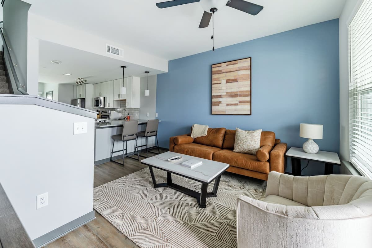A modern living room with a brown sofa, a white coffee table, and a patterned rug.