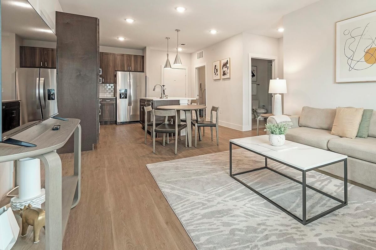 Una sala de estar moderna con sofá, mesa de centro y zona de comedor.