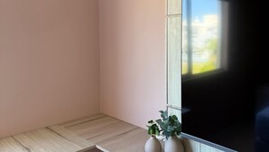 Een moderne woonkamer met een flatscreen televisie aan een houten wand, een inbouwbank en twee potplanten.