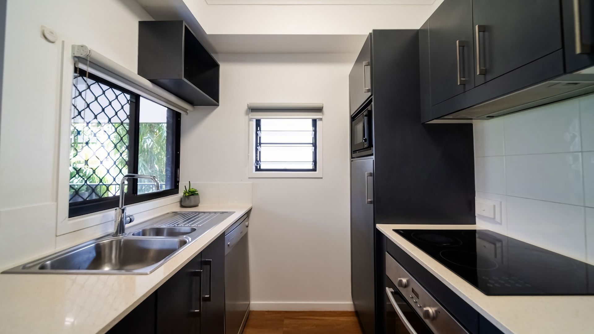 A compact kitchen with a sink, stove, and microwave.