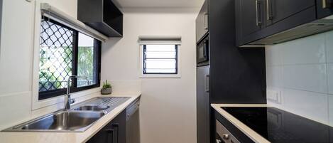 A compact kitchen with a sink, stove, and microwave.