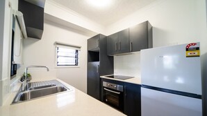 A modern kitchen with a stainless steel sink, a built-in oven, and a refrigerator. - North Ward Coastal Retreat Near The Strand (North Ward)