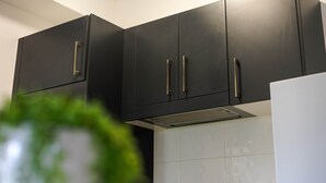 A kitchen with black cabinets and a white refrigerator. - North Ward Coastal Retreat Near The Strand (North Ward)