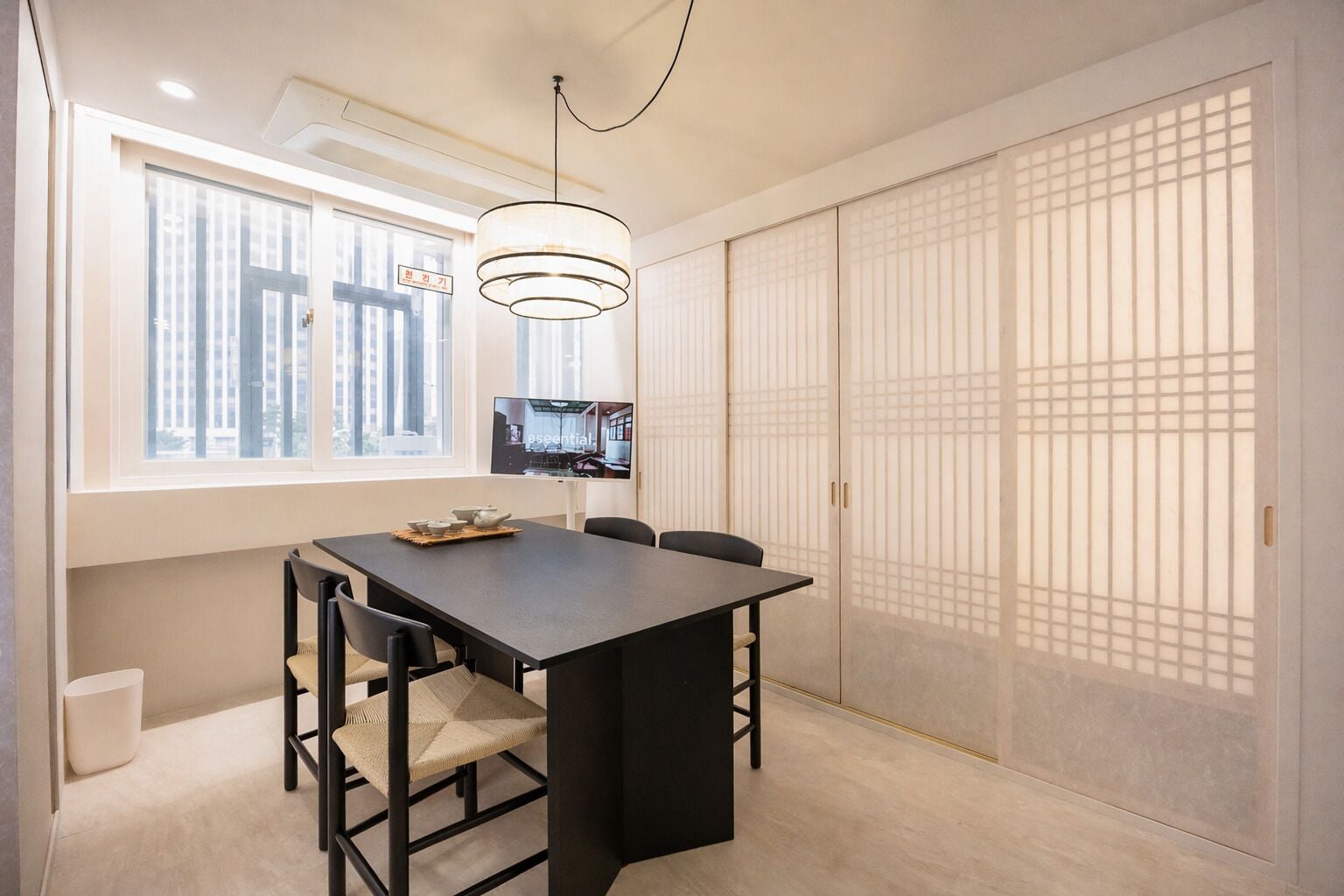 A modern dining area with a dark table, chairs, and a hanging light fixture.