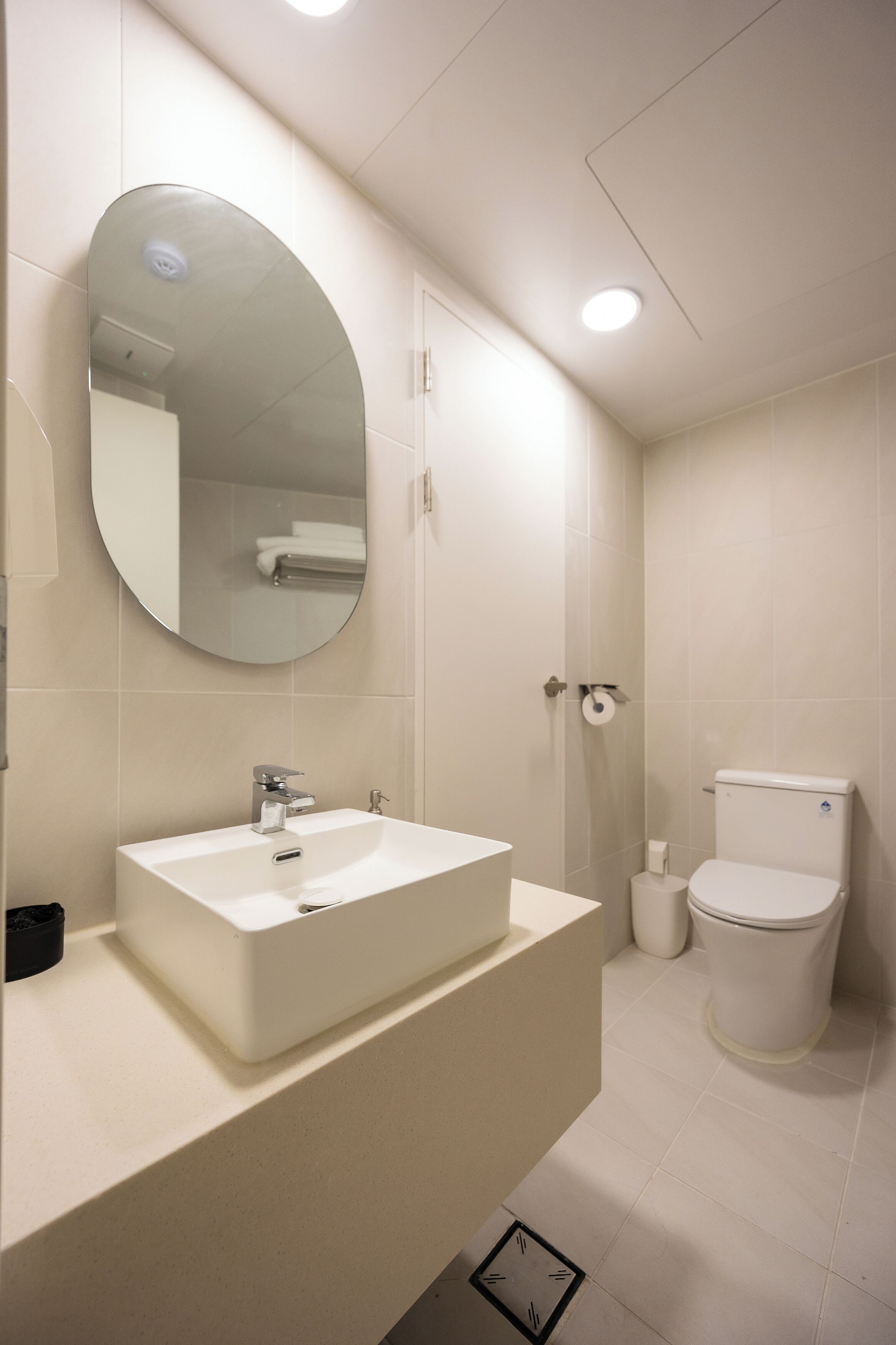 A modern bathroom with a white sink, mirror, toilet, and shower.