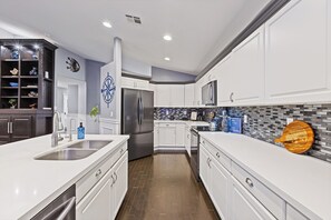 A modern kitchen with white cabinetry, stainless steel appliances, and a tiled backsplash. - Wellness Retreat • Hot Tub + Cold Plunge, Downtown Gilbert! (Gilbert)