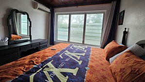 A bedroom with a bed, a dresser, a mirror, a ceiling fan, and a window with blinds. - Seaview Condo Ocho Rios with private access to Mahogany beach (Ocho Rios)