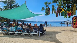 A beach with lounge chairs and a shaded area. - Seaview Condo Ocho Rios with private access to Mahogany beach (Ocho Rios)
