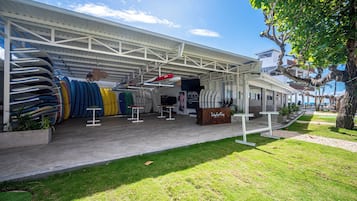 A covered outdoor area with a variety of kayaks and paddleboards, a seating area, and a sign that reads "The Lodge."