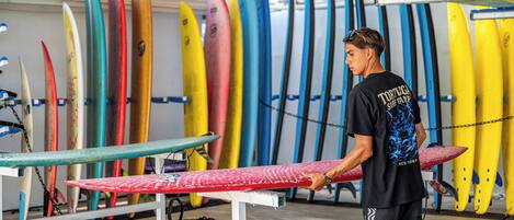 Uma loja de pranchas de surf com diversas pranchas coloridas expostas em estantes.