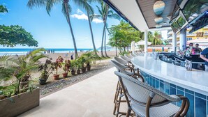 A beachside bar with outdoor seating, a view of the beach, and palm trees. - Ozeano Jaco (Jacó)