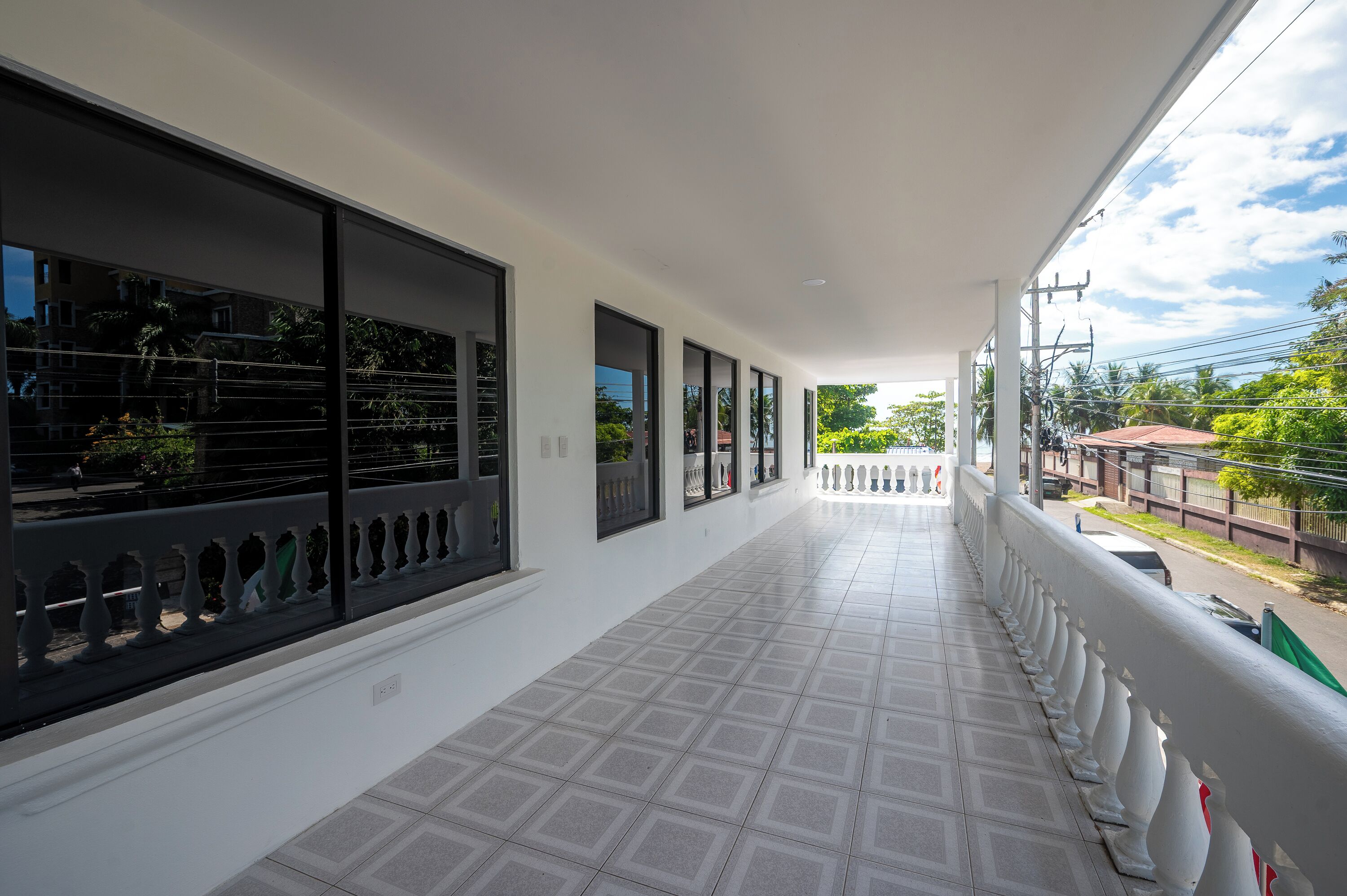 A corridor with large windows, a tiled floor, and a railing.
