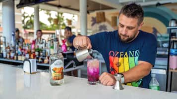 A bartender pouring a drink into a tall glass.