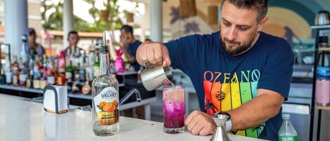 A bartender pouring a drink into a tall glass.