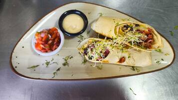 A plate with two wraps and a small bowl of salsa.