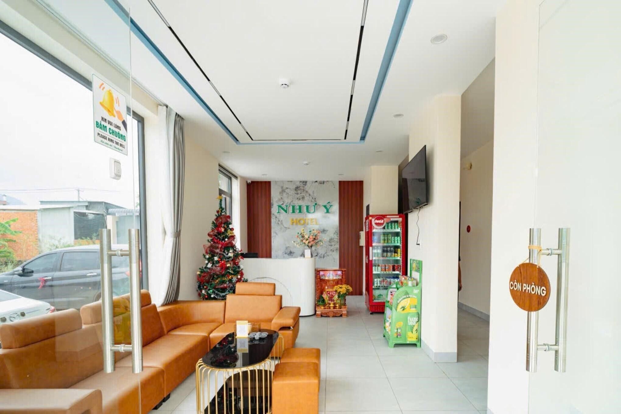 Ein Hotel-Empfangsbereich mit Weihnachtsbaum, einer Rezeption, einem Fernseher und einem Getränkeautomaten.