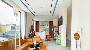 Ein Hotel-Empfangsbereich mit Weihnachtsbaum, einer Rezeption, einem Fernseher und einem Getränkeautomaten.