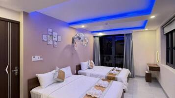 A hotel room with a large bed, bedside tables, a small desk, and a window with curtains.