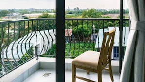 Un balcón con una silla y vistas a la ciudad, con una cerca verde.