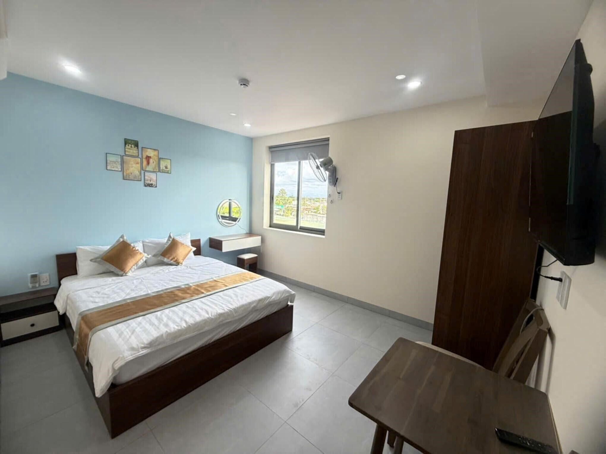 Habitación de hotel con cama, mesita de noche, escritorio y televisor montado en la pared.