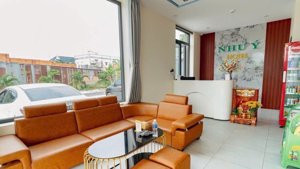 Un vestíbulo de hotel con un conjunto de sofás, un mostrador de recepción y un refrigerador de Coca-Cola.