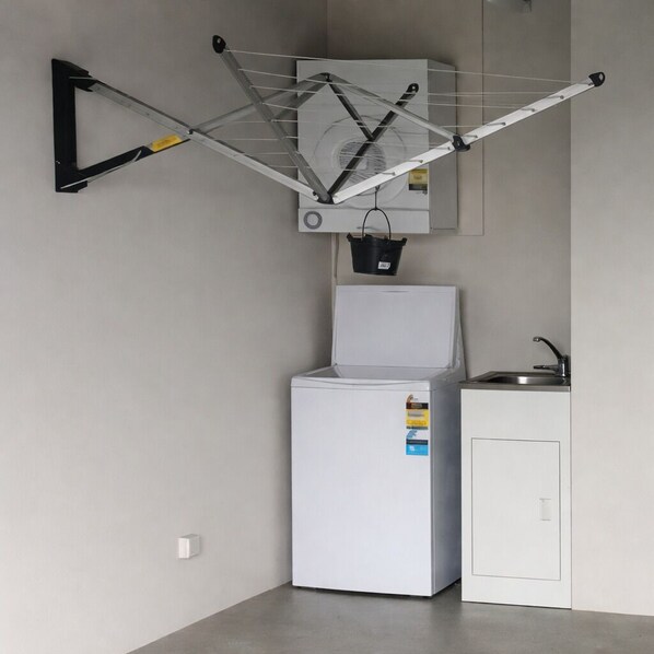 Cocina compacta con un refrigerador blanco, un lavabo y un tendedero.
