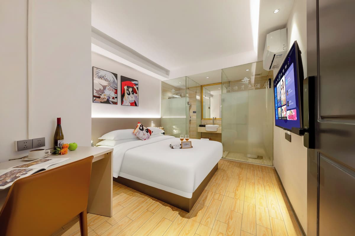 Una habitación de hotel moderna con una cama, un escritorio, un televisor y una cabina de ducha de vidrio.