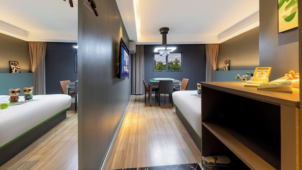 A hotel room with two beds, a desk, a chair, a TV, and a window with a view of trees. - Andy International Hotel Shenzhen (Shenzhen)