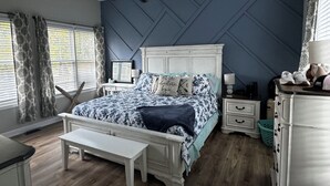 A bedroom with a bed, a desk, a bench, a dresser, a nightstand, and a ceiling fan. - Large Pond View, 2 min to Lake! Hot tub (Nancy)