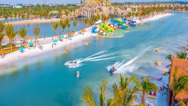 Parque acuático con un tobogán gigante, una playa de arena y una piscina azul cristalina.