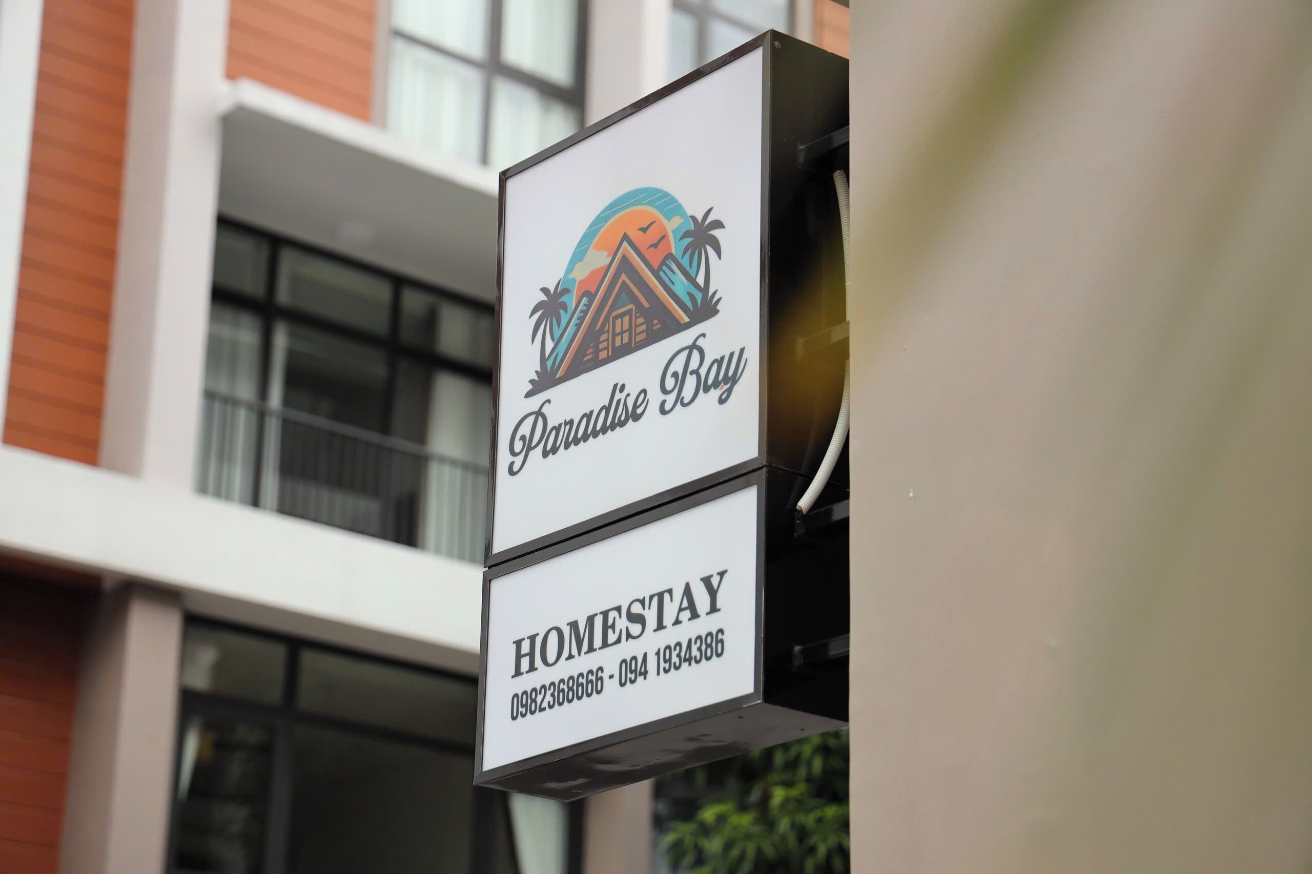 Μια πινακίδα για το κατάλυμα «Paradise Bay Homestay» με τους αριθμούς τηλεφώνου επικοινωνίας.
