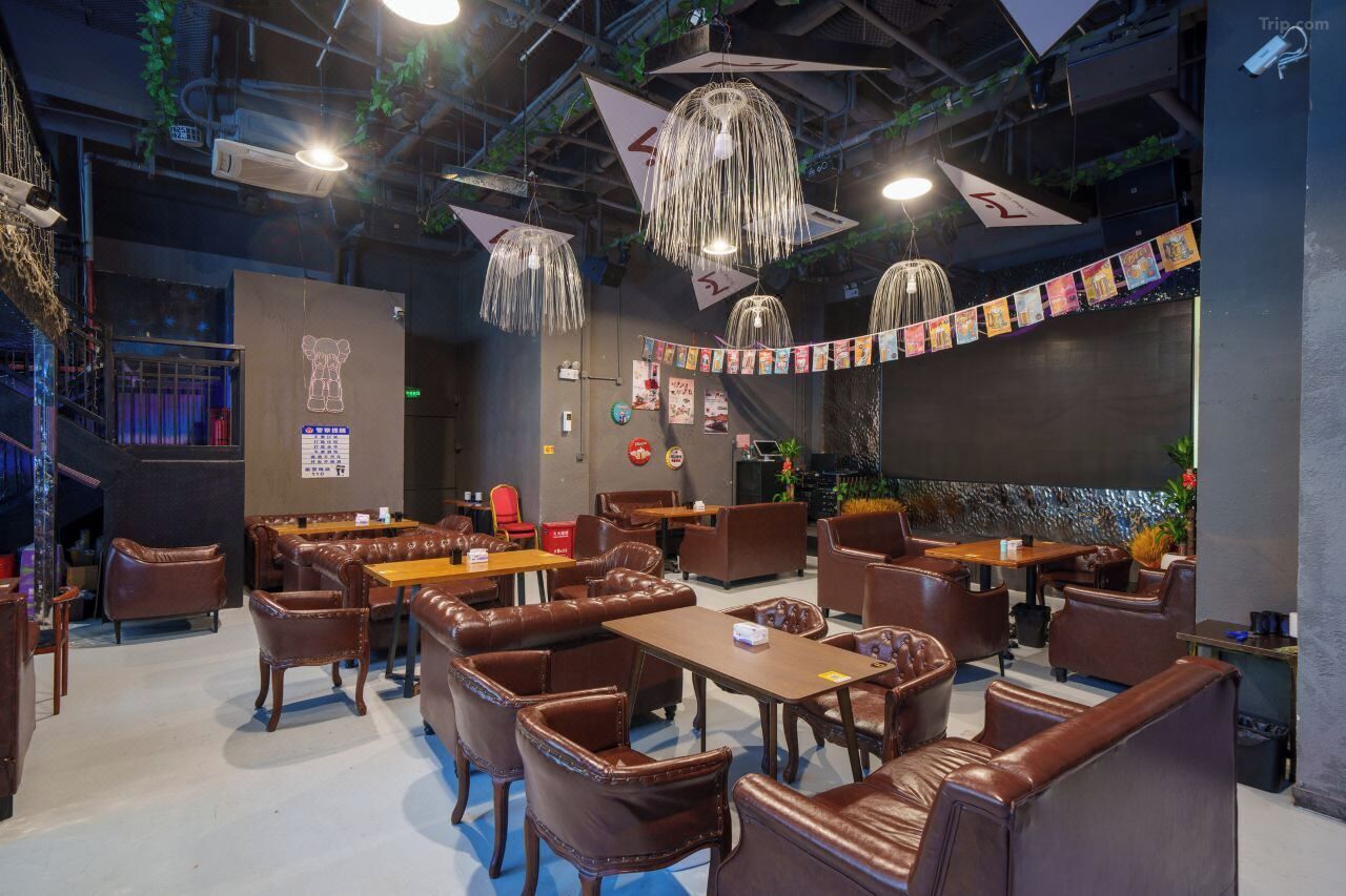 A restaurant with leather booths and tables, hanging light fixtures, and a banner with pictures.