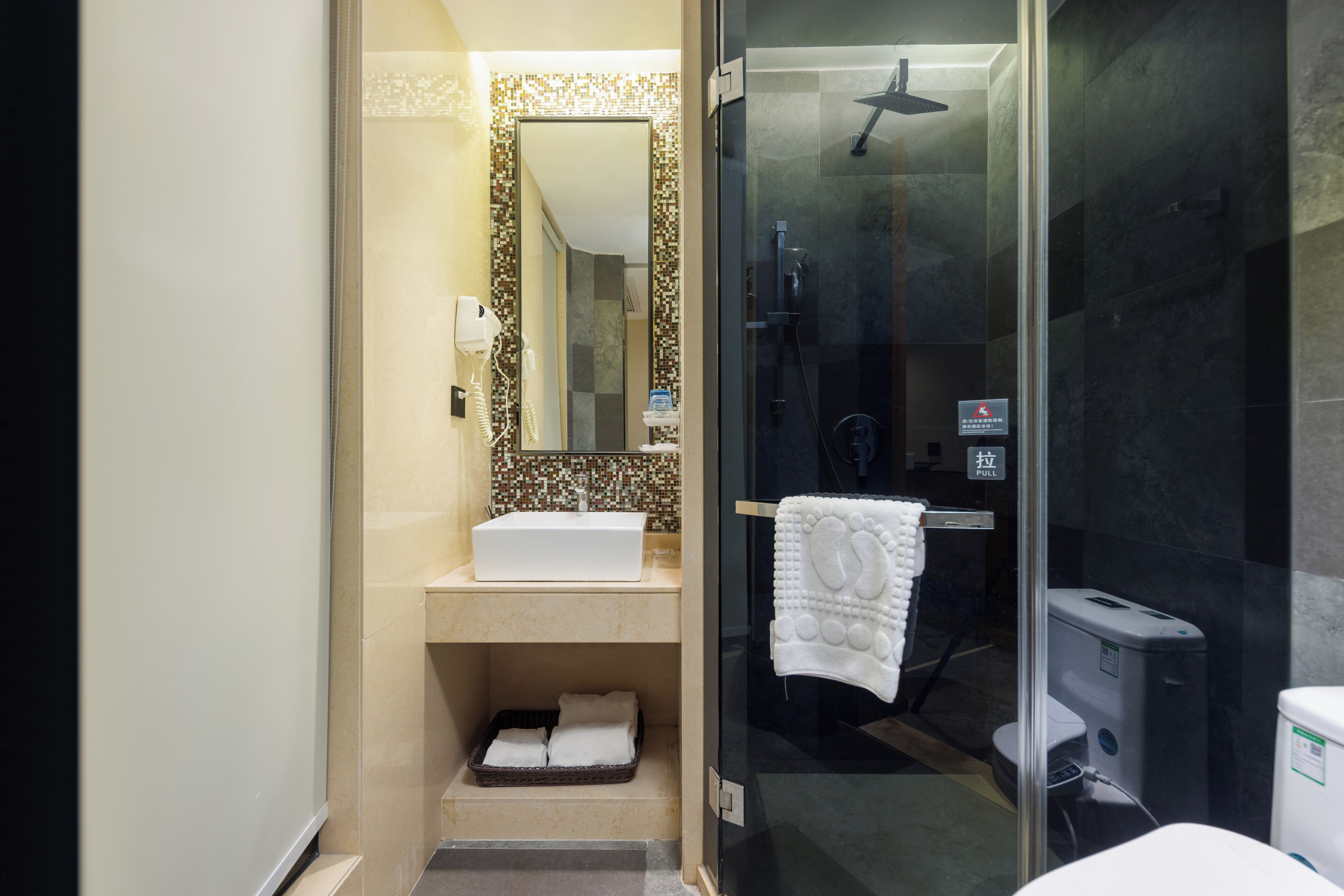 A bathroom with a white sink, a mirror, a glass shower enclosure, and a towel rack.
