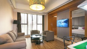 Ein modernes Hotelzimmer mit einer Couch, Sesseln, einem Couchtisch, einem Fernseher, einem Bett und einem Billardtisch.