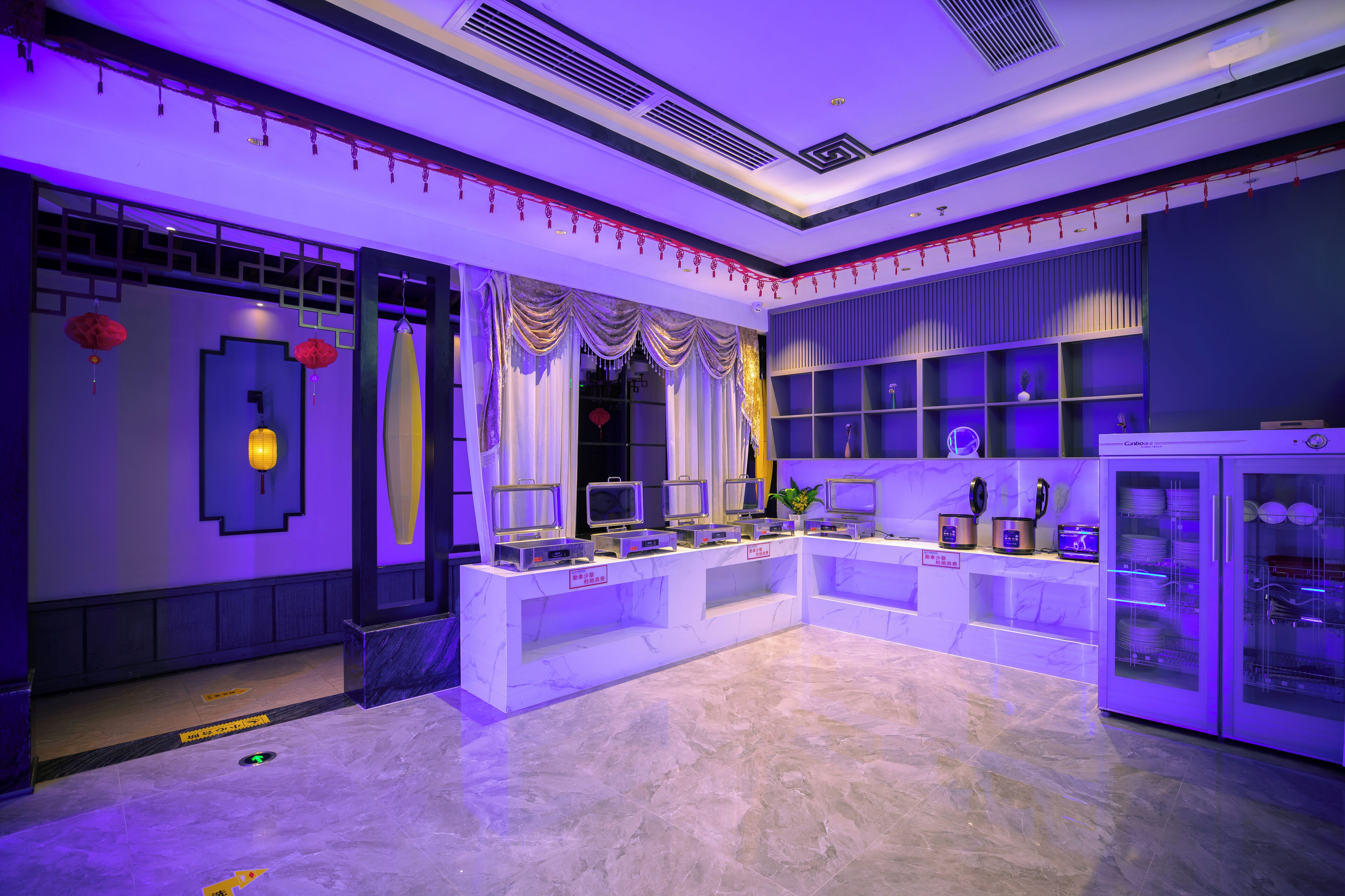 A modern hotel lobby with a marble floor, a reception desk, and a display of televisions.