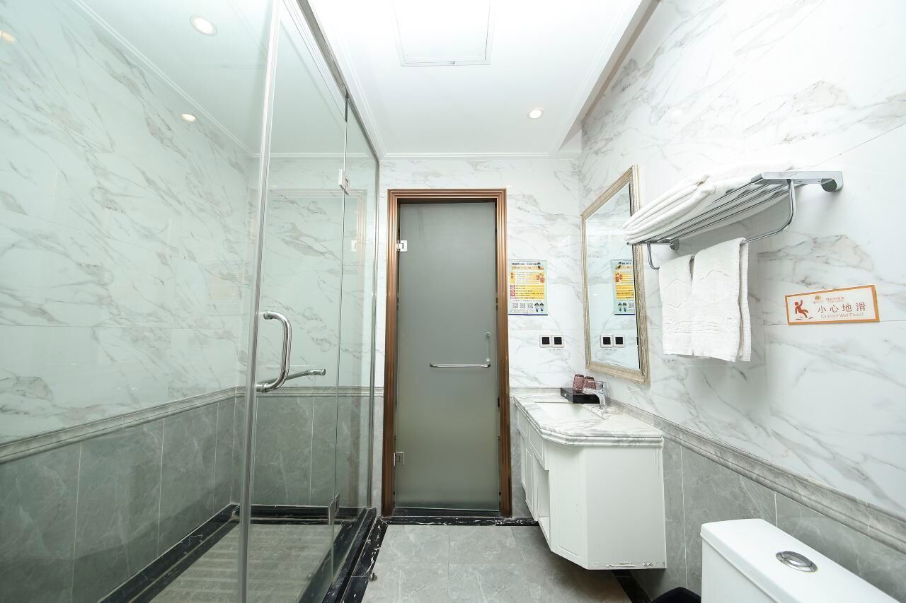 A bathroom with a glass shower enclosure, a sink with a mirror, and a toilet.