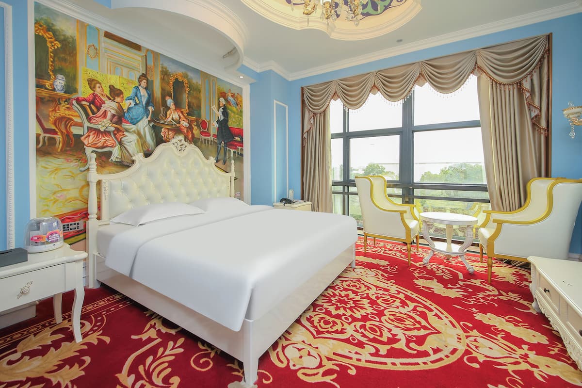 Ein Hotelzimmer mit einem großen Bett, einem roten Teppich, einem Gemälde an der Wand und Blick ins Freie durch ein Fenster.