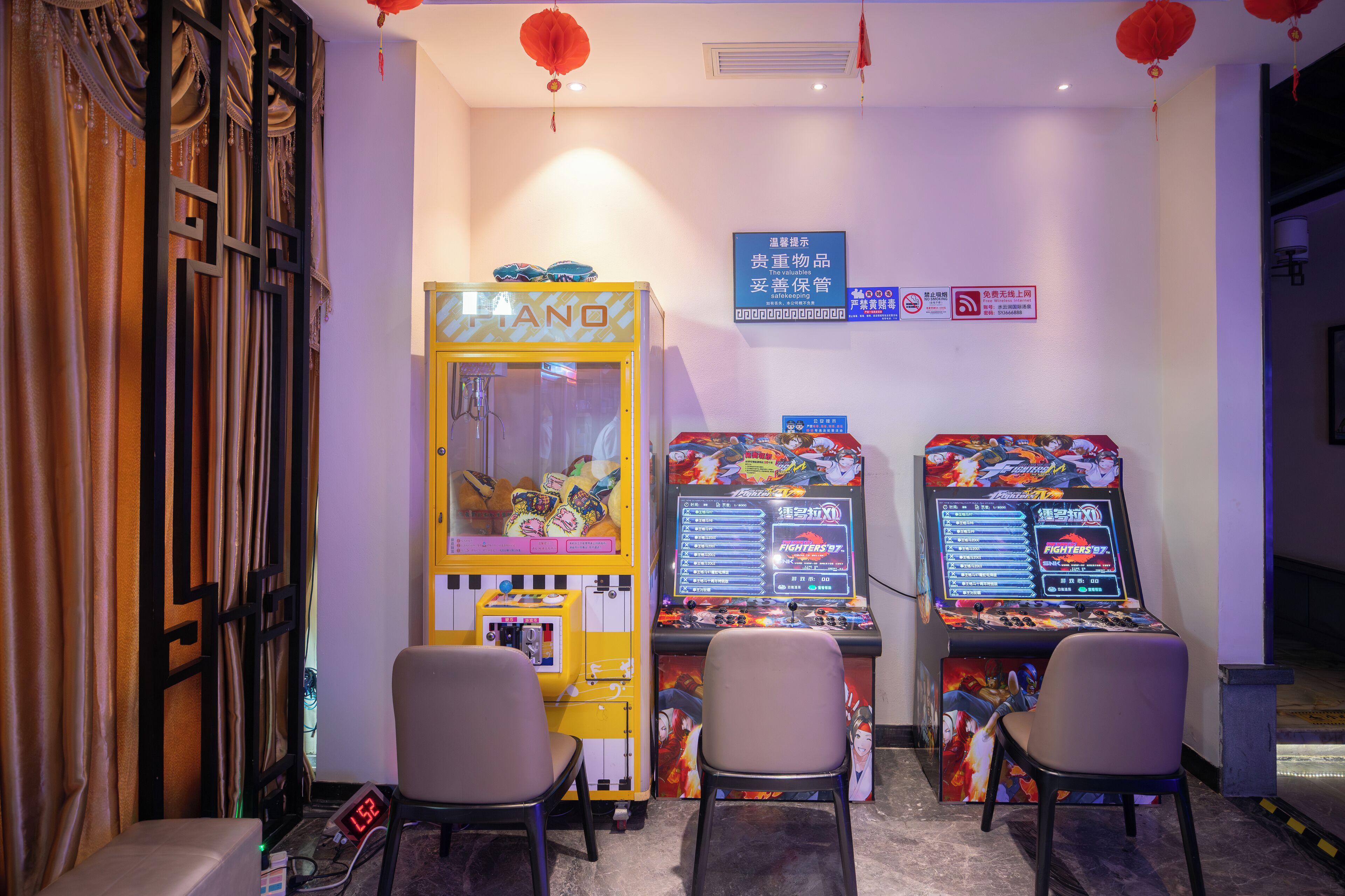 Een kamer met twee speelautomaten, een digitale klok en twee stoelen.