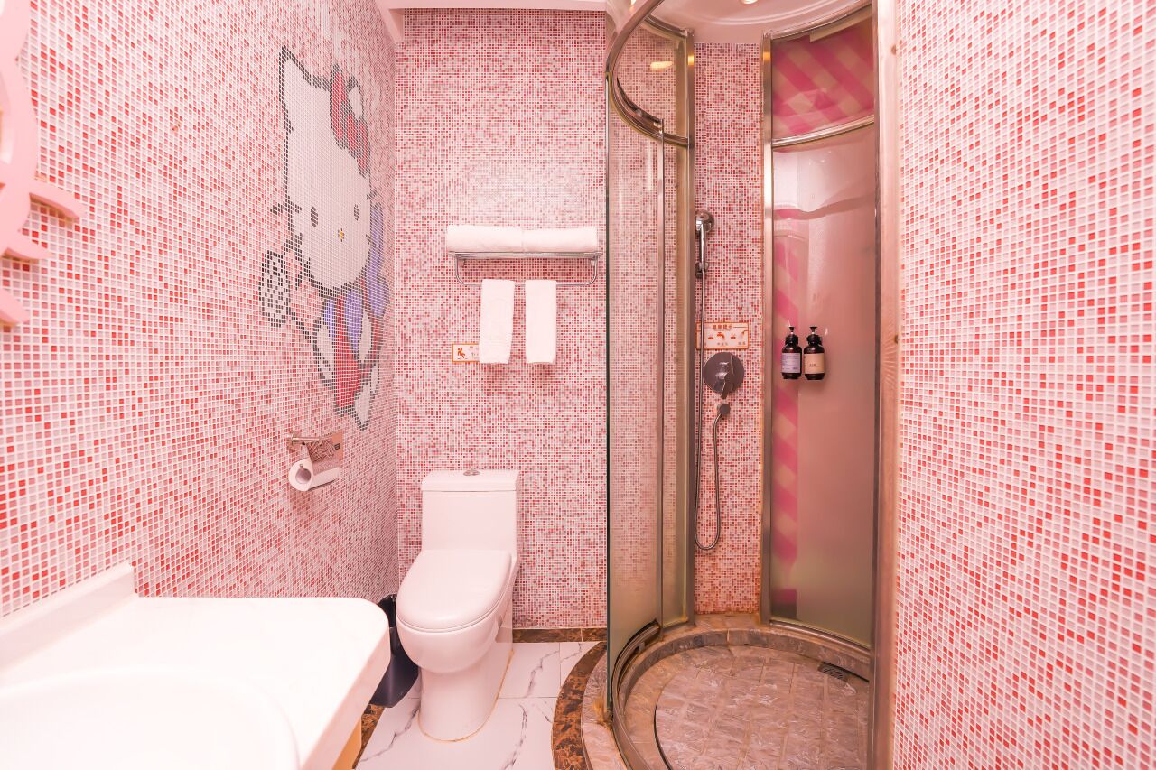 A bathroom with a mosaic tile wall, a toilet, a shower, and a sink.