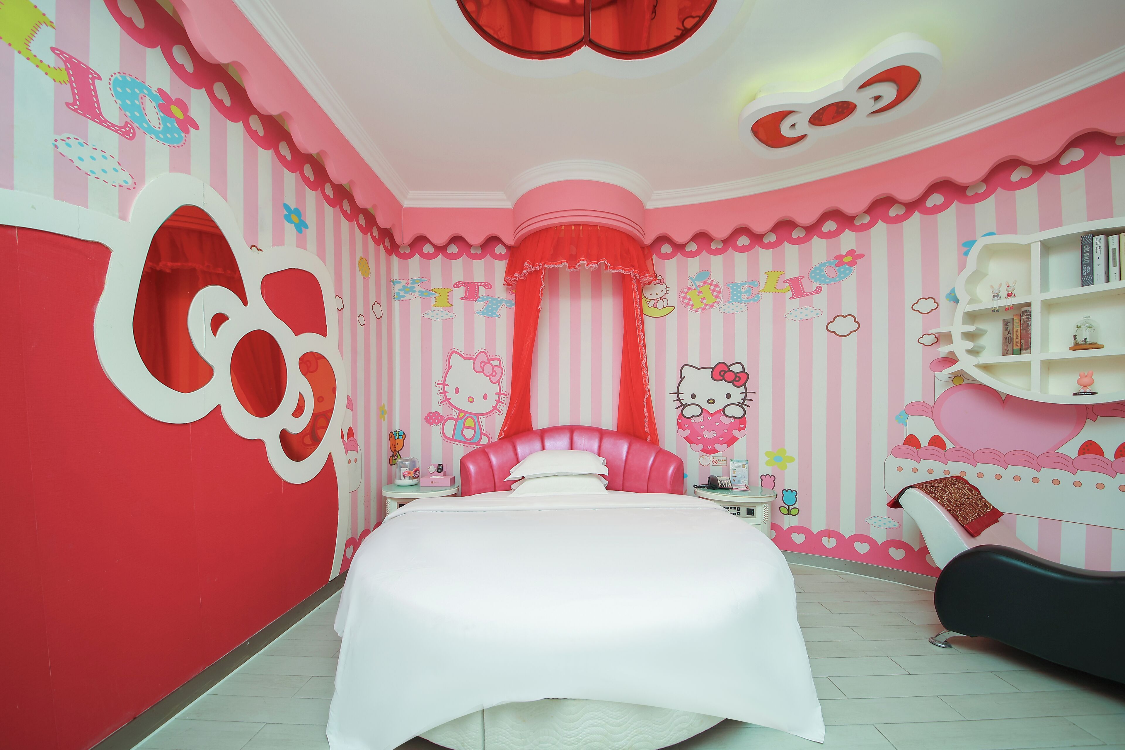 Une chambre à coucher aux rayures roses et blanches, avec un lit, une table de chevet, une chaise et une étagère contenant des livres et des objets décoratifs.