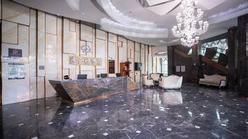 Um hall de hotel moderno, com uma receção de mármore, área de estar e um candelabro.