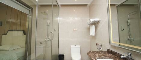 A hotel bathroom with a glass-enclosed shower, a toilet, and a sink with a marble countertop.