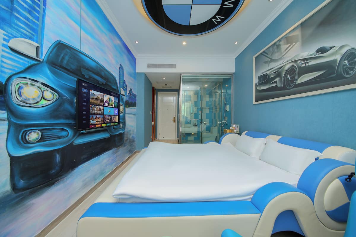Ein modernes Hotelzimmer mit einem großen Bett, einem Wand-Fernseher und einer Wandmalerei mit einem BMW-Auto.
